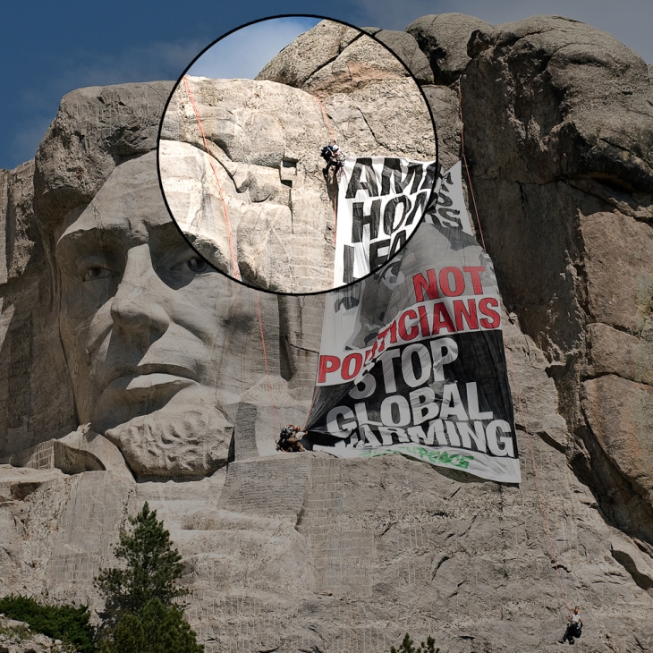 A climber fixes a line to the corner of a banner on Mount Rushmore following a tension traverse.
